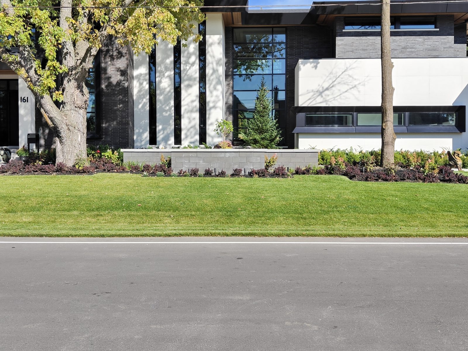 Front yard landscaping project — interlocking retaining wall, garden beds and manicured lawn in Etobicoke